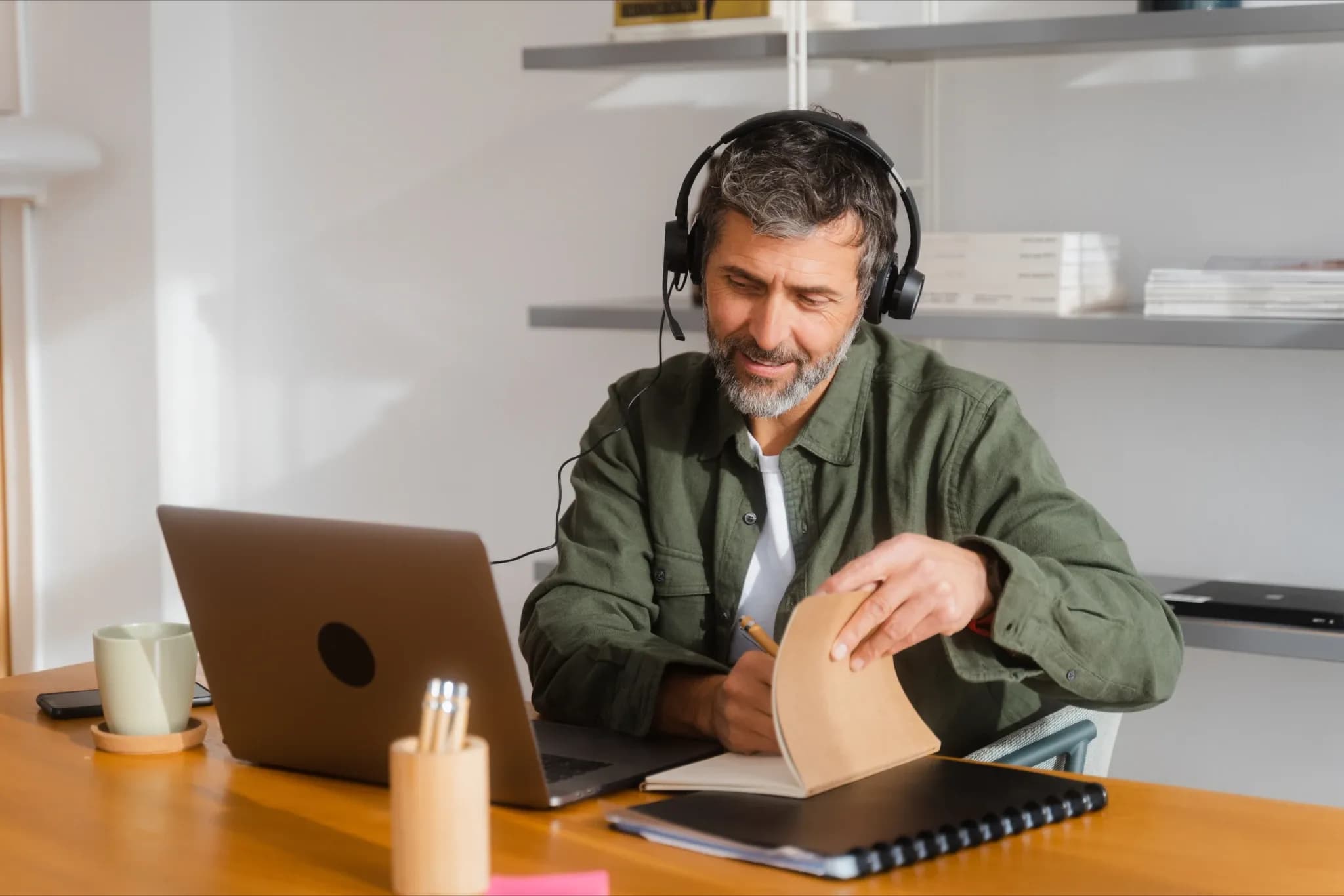 A telemarketer using a laptop and headset, taking notes during a call, representing effective telemarketing services.